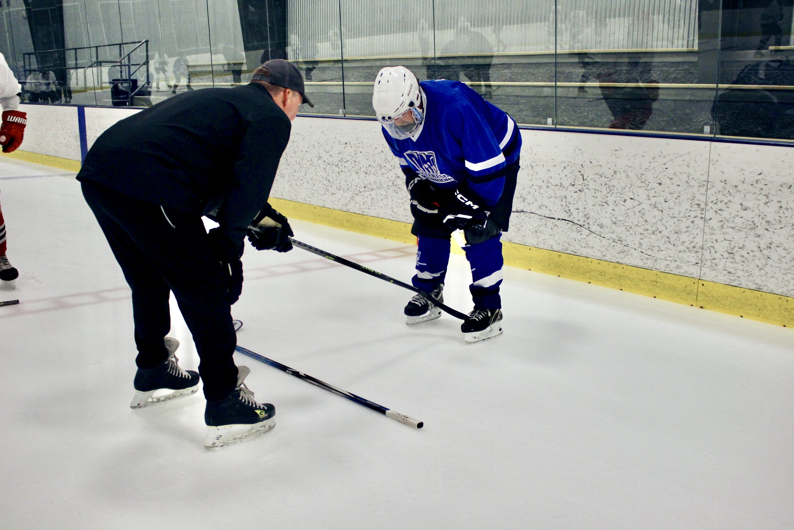 Coach Casey helps a player with his skating stride